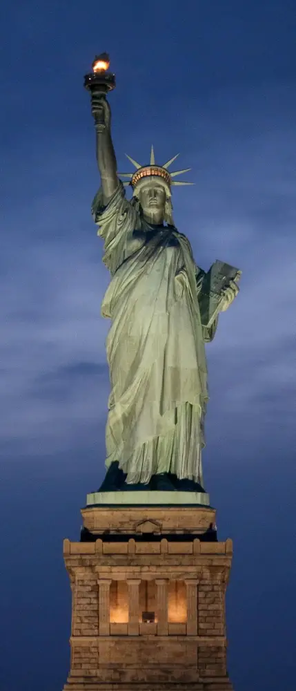 Statua della Libertà illuminata di notte, simbolo di speranza e libertà negli Stati Uniti.